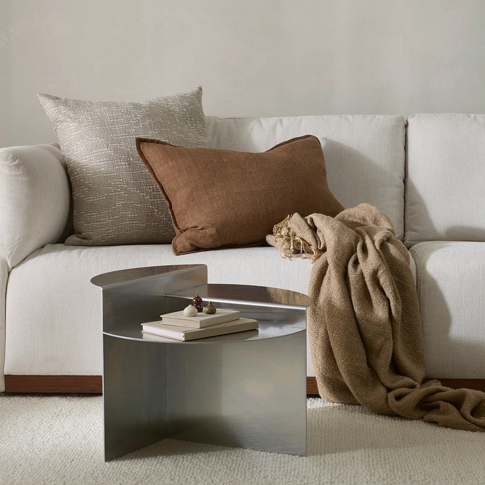 Neutral sofa with a chestnut brown linen cushion and beige cushion, with a blanket, and a metal coffee table.