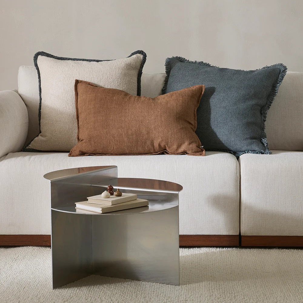 Neutral sofa with decorative cushions and a metallic coffee table in a living room setting.
