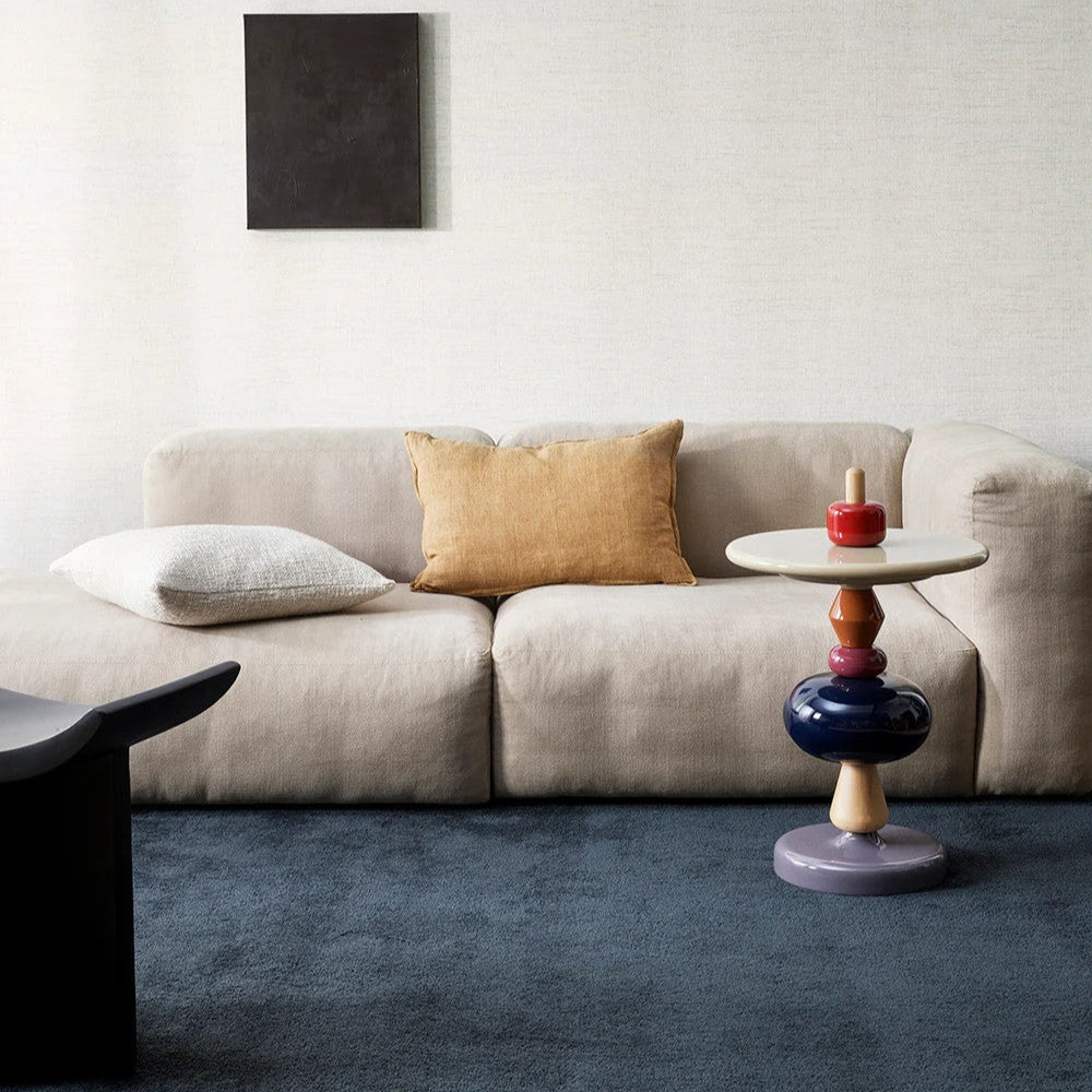 Cumin linen cushion on a beige sofa with a decorative side table in a modern living room setting.