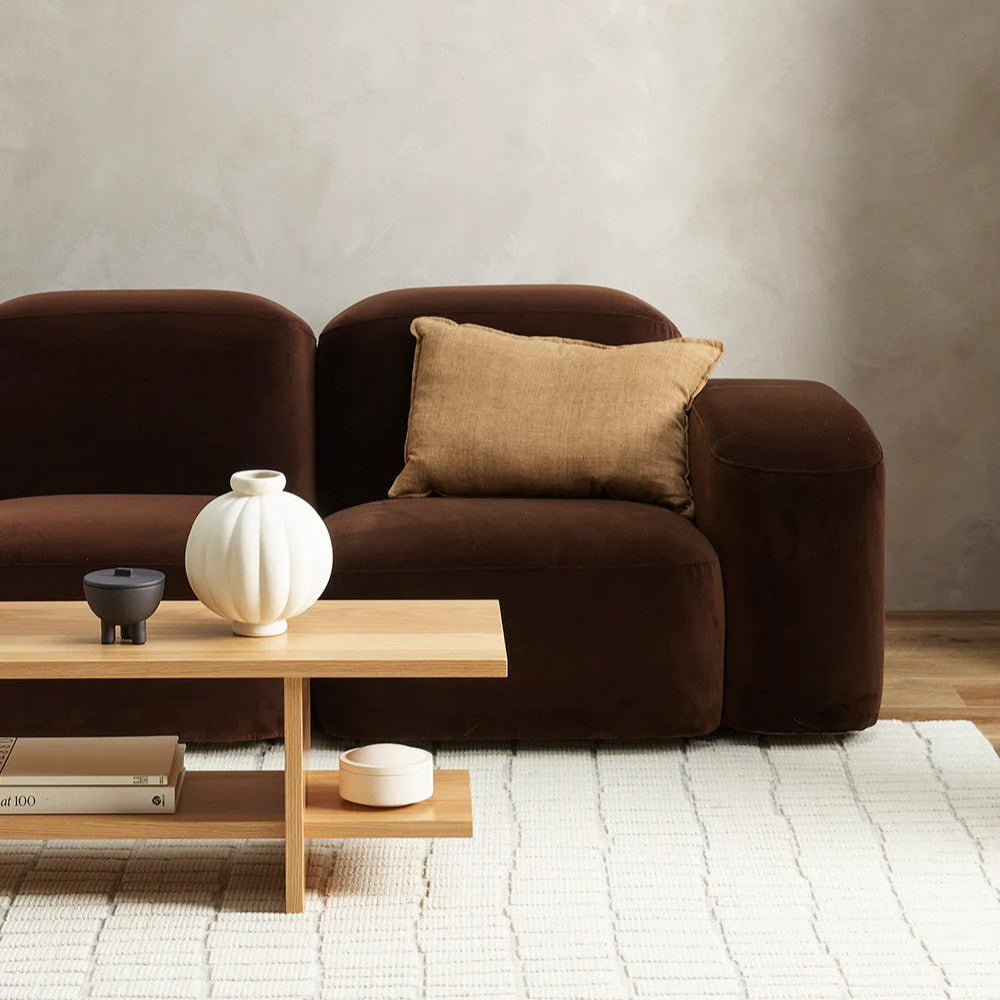 Brown sofa with a wooden coffee table and a cumin linen cushion in a minimalistic living room.