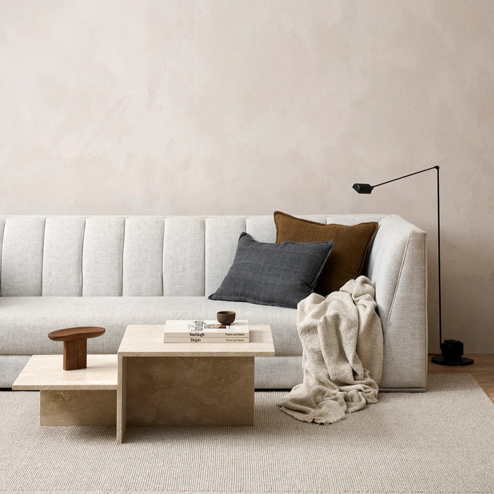Modern living room with a beige sofa, slate grey linen cushion, wooden coffee table, and decorative items.
