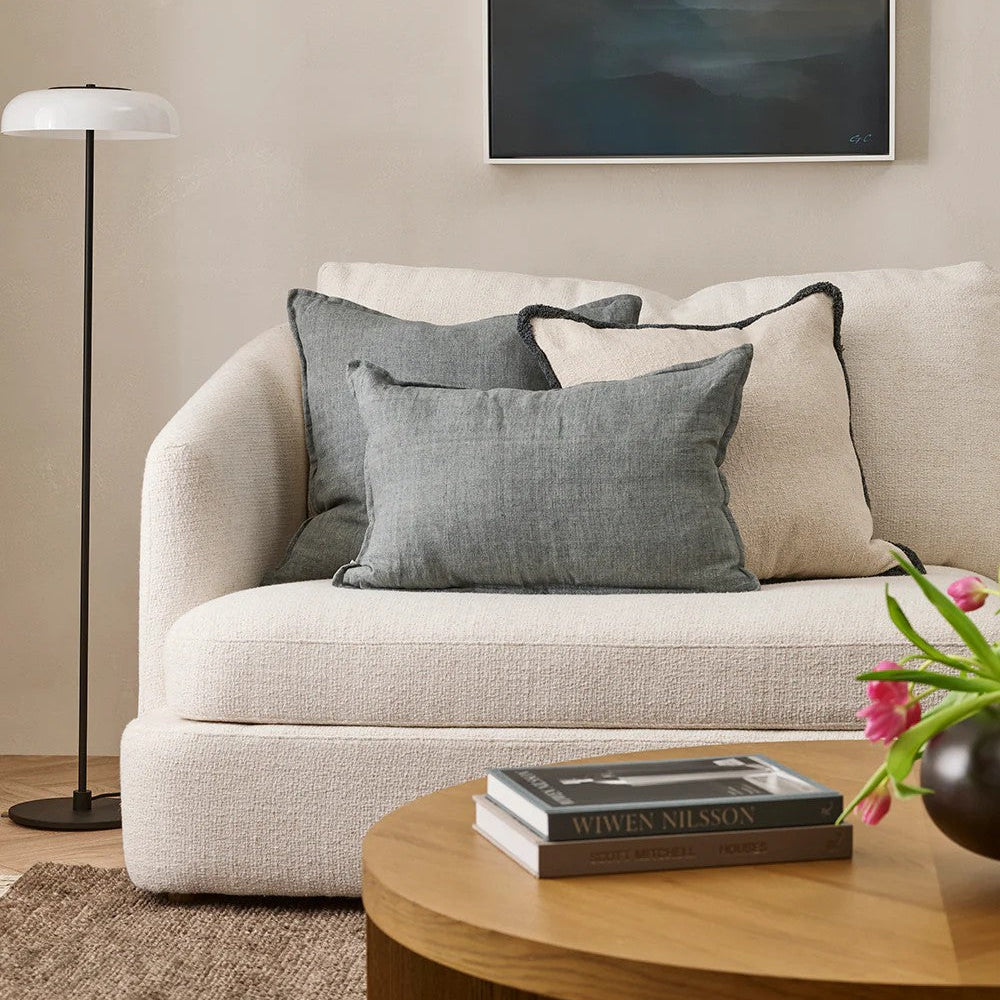 Living room with beige sofa, gray cushions, wooden coffee table, and abstract painting on wall.
