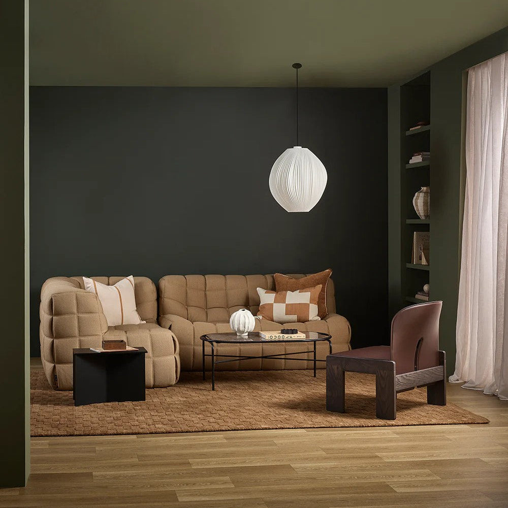 Modern living room with ginger sofa, armchair, toffee coloured floor rug and coffee table under a white pendant light.