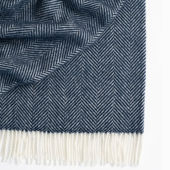 Navy throw blanket with a herringbone weave and white fringe.