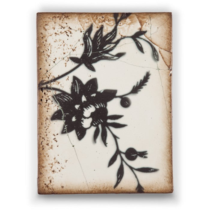 Decorative tile with black floral design on a textured beige background