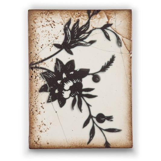 Decorative tile with black floral design on a textured beige background
