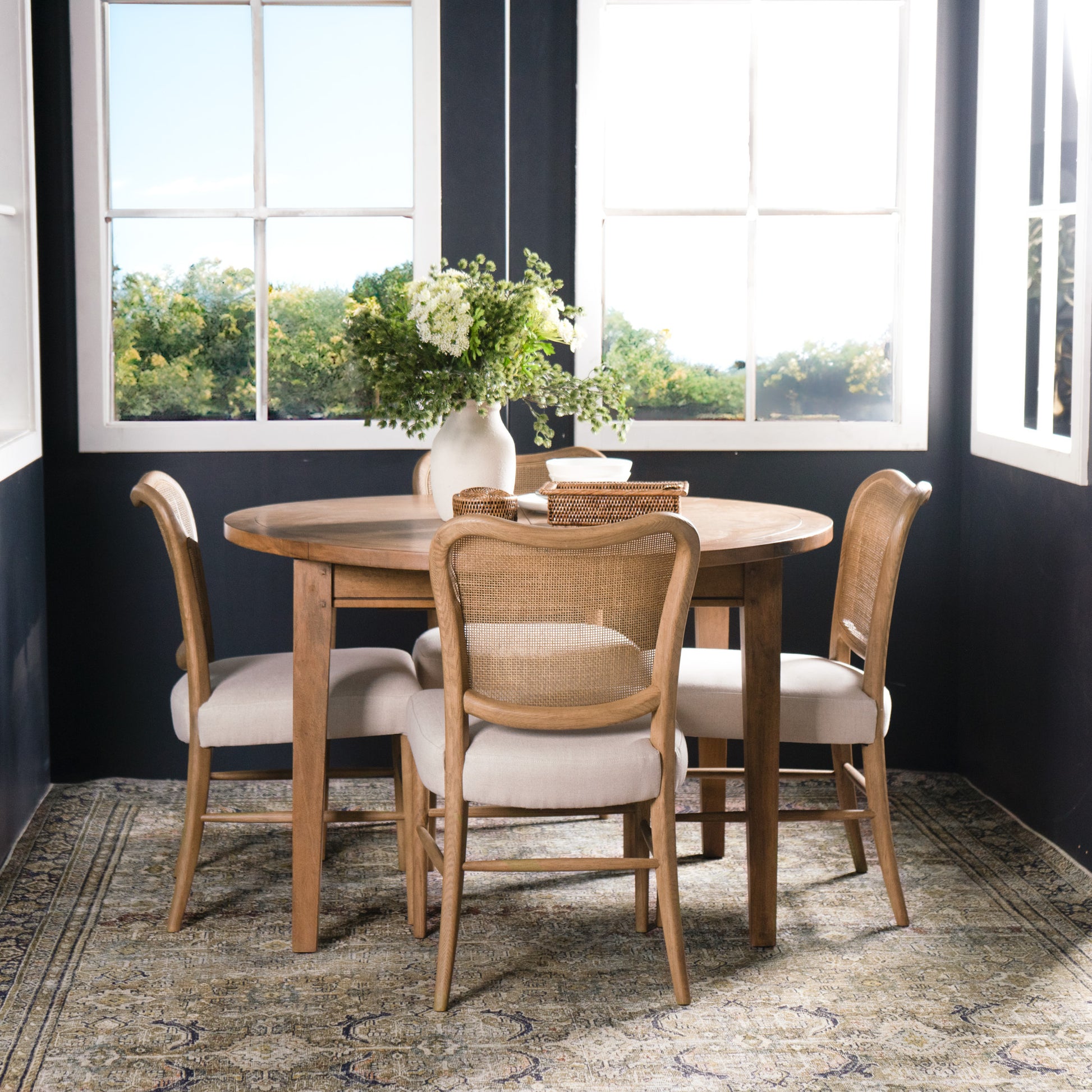 Dining area with wooden table and chairs in a room with large windows.