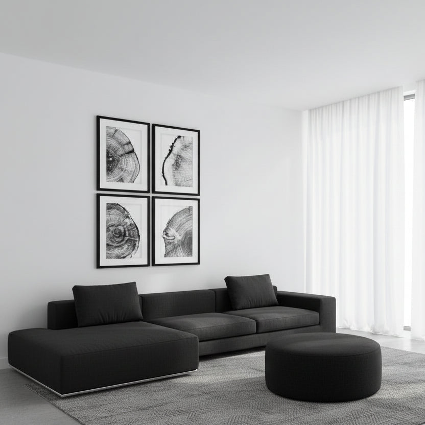 Modern living room with a black sectional sofa, ottoman, and framed art on a white wall.