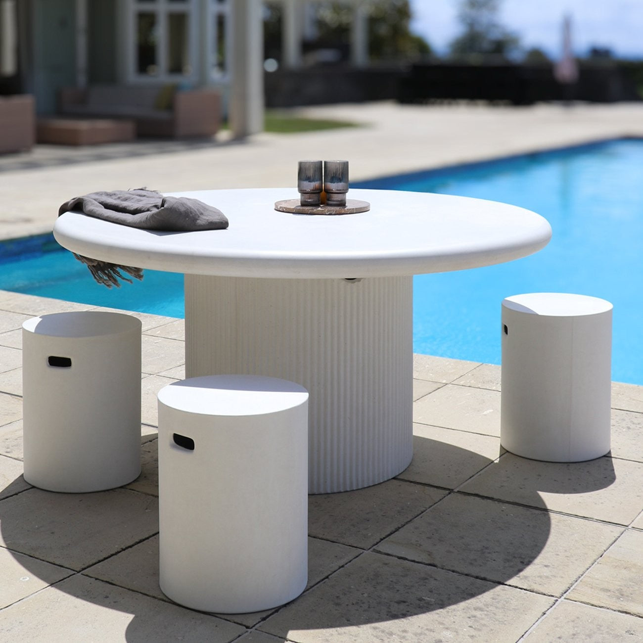 White outdoor table with stools by a poolside