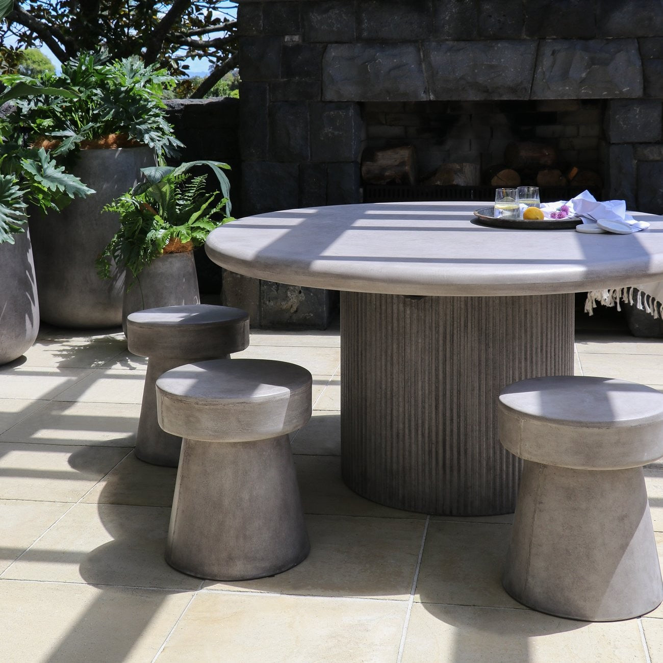 Outdoor patio set with a round table and stools on a stone patio.