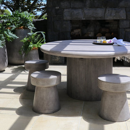 Outdoor patio set with a round table and stools on a stone patio.