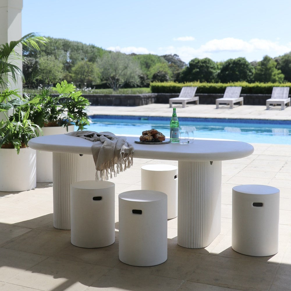 White outdoor table with stools near a pool