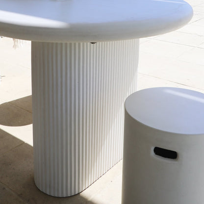 White textured pedestal base table and coordinating stool on a light tiled floor