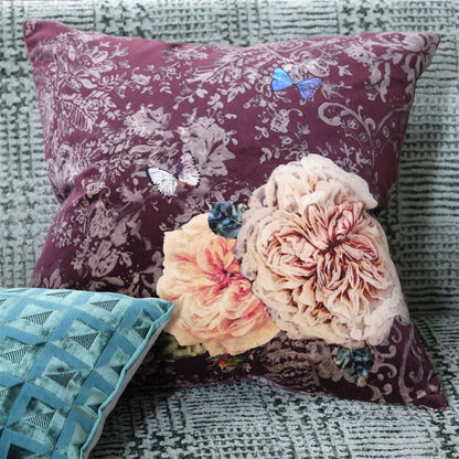 Decorative pillows with floral patterns and butterfly designs on a textured surface.