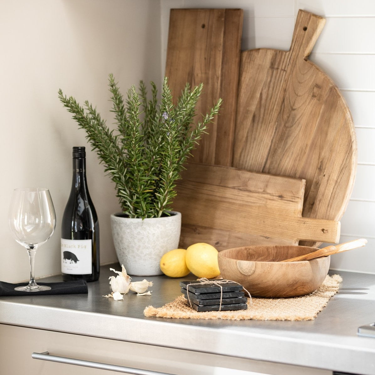 Kitchen counter with wooden cutting boards, lemons, a plant, and a bottle of wine.