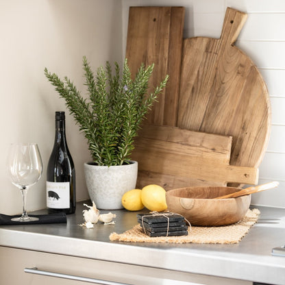Kitchen counter with wooden cutting boards, lemons, a plant, and a bottle of wine.
