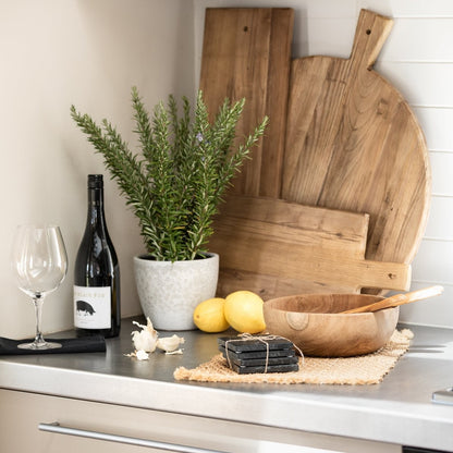Kitchen counter with wooden cutting boards, lemons, a plant, and a bottle of wine.