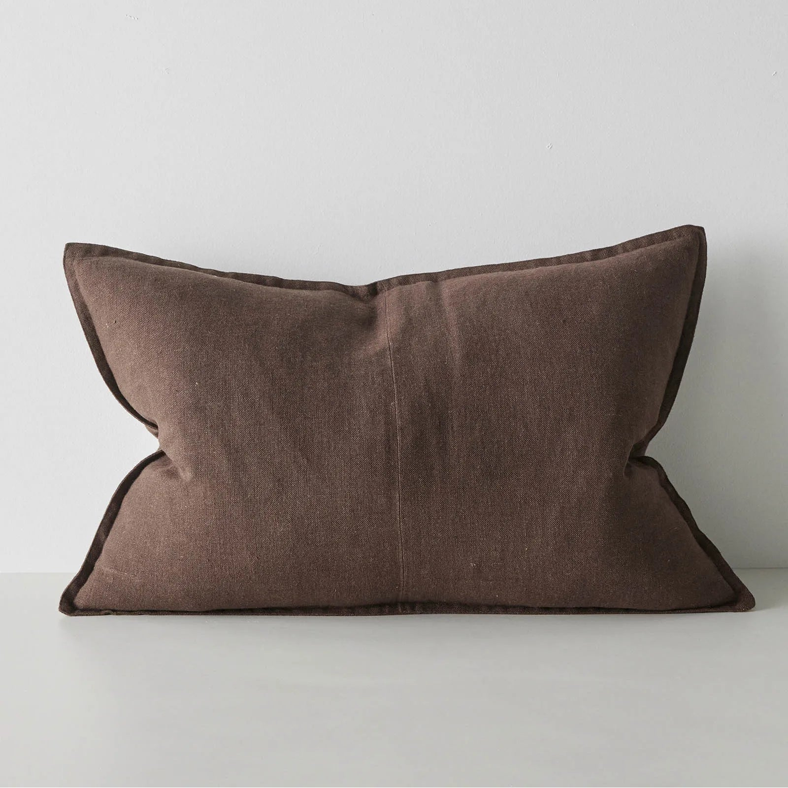 Brown lumbar cushion on a white surface with a light grey background