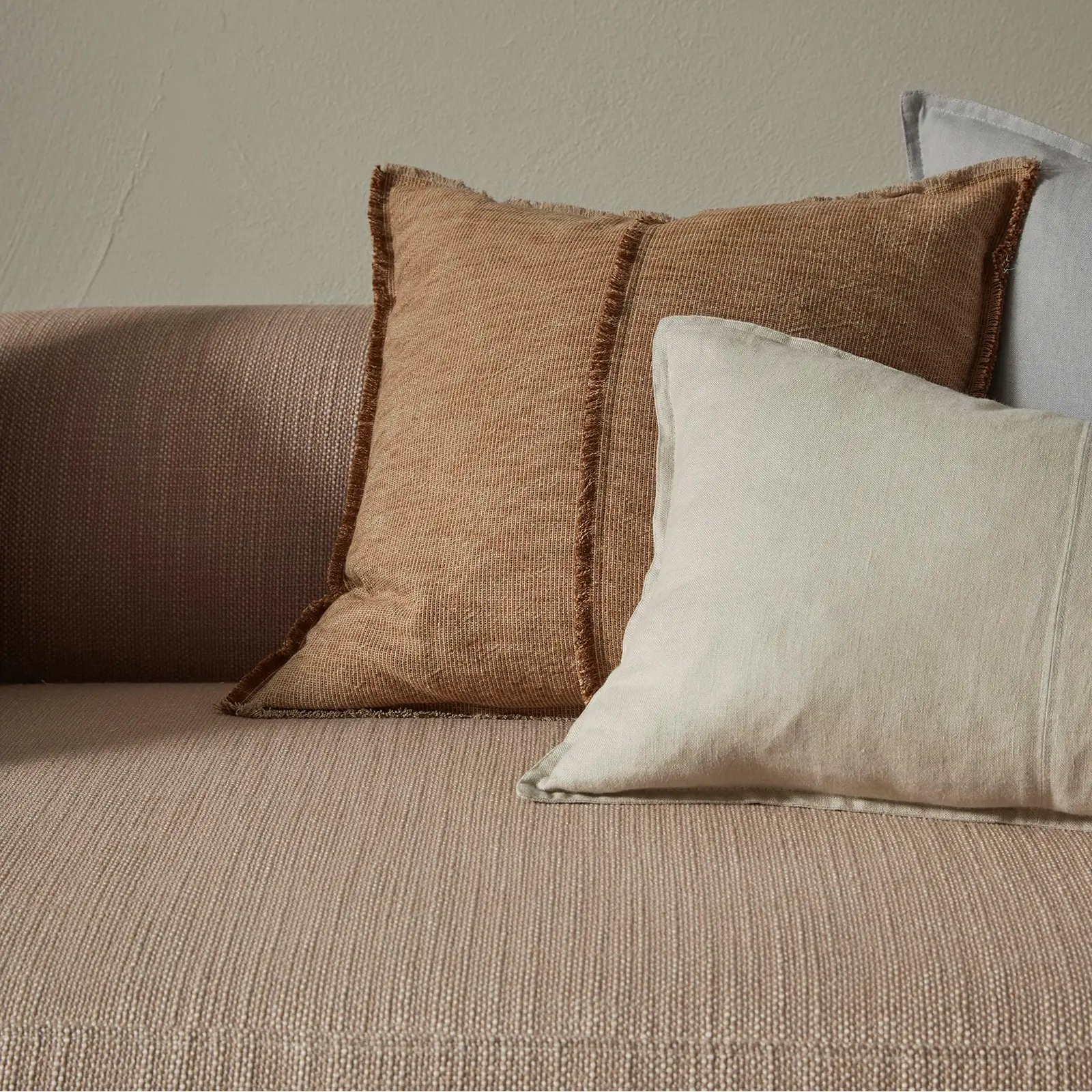 Textured pillows on a sofa against a neutral wall