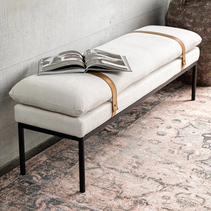 Ivory bench seat with an open magazine, against a grey wall.