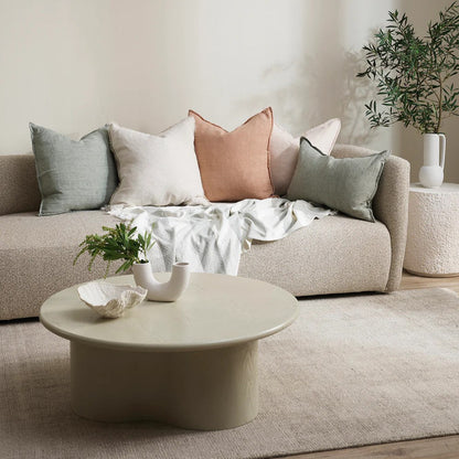 Living room with a beige sofa, coffee table, and decorative cushions.