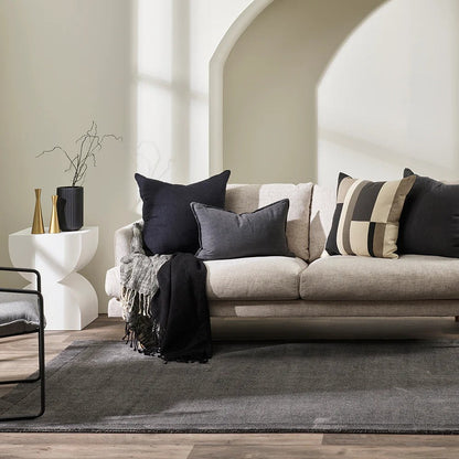 Charcoal floor rug with a Beige sofa and decorative cushions in a modern living room setting.