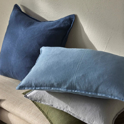 Three pillows in blue, gray, and green on a beige surface