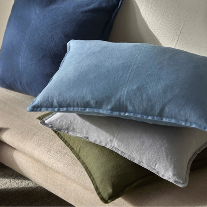 Three pillows in blue, gray, and green on a beige surface