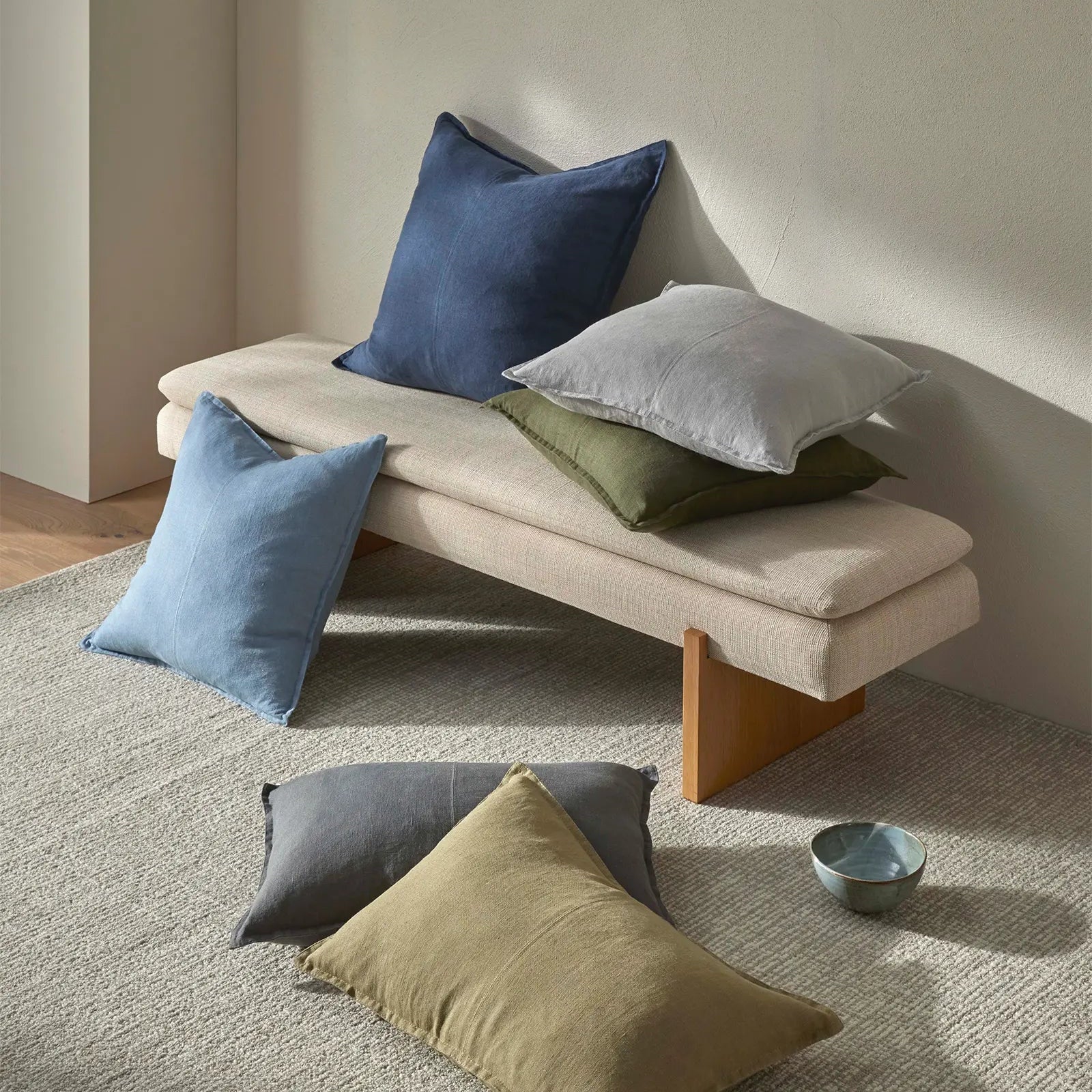 Beige bench with colorful cushions on a neutral background
