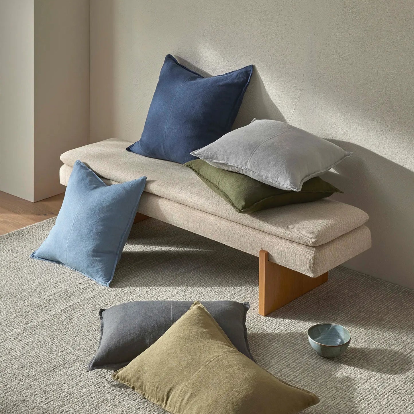 Beige bench with colorful cushions on a neutral background