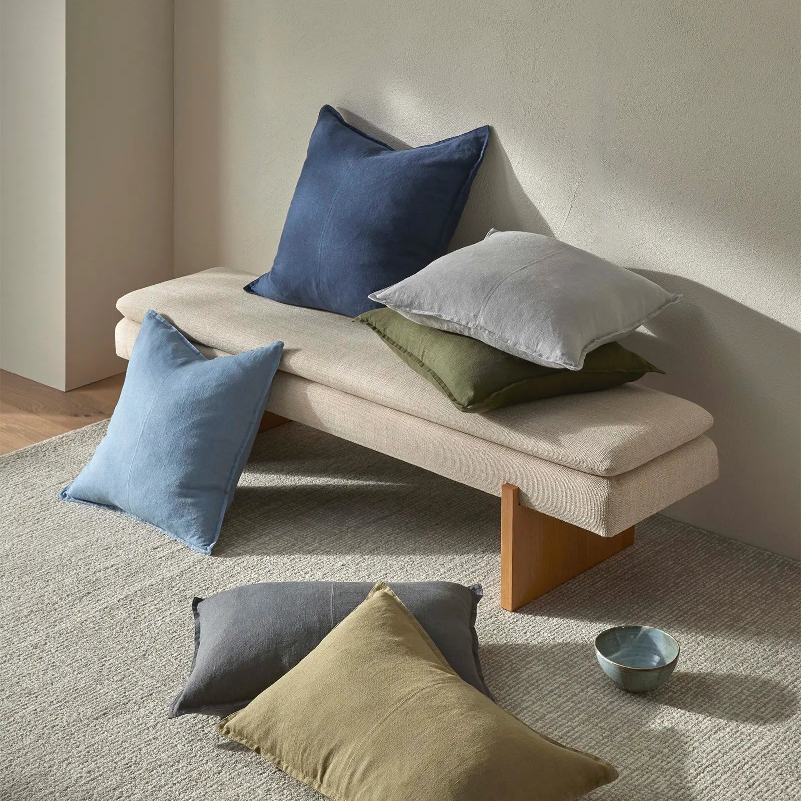 Beige bench with colorful cushions on a neutral background