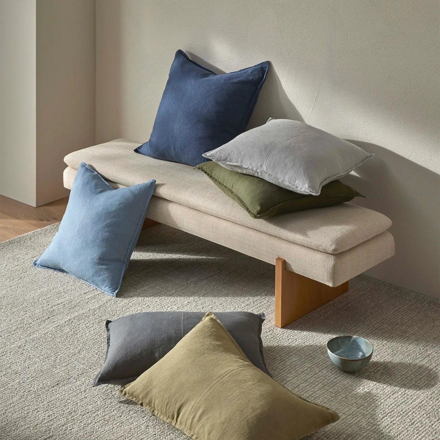 Beige bench with colorful cushions on a neutral background