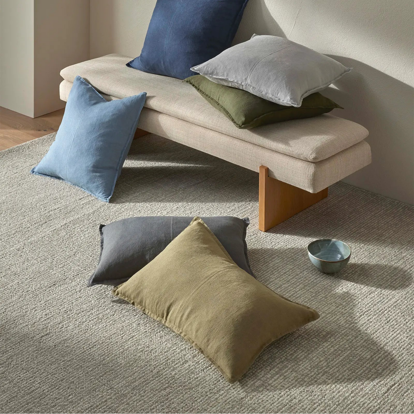 Beige bench with colorful cushions on a neutral background