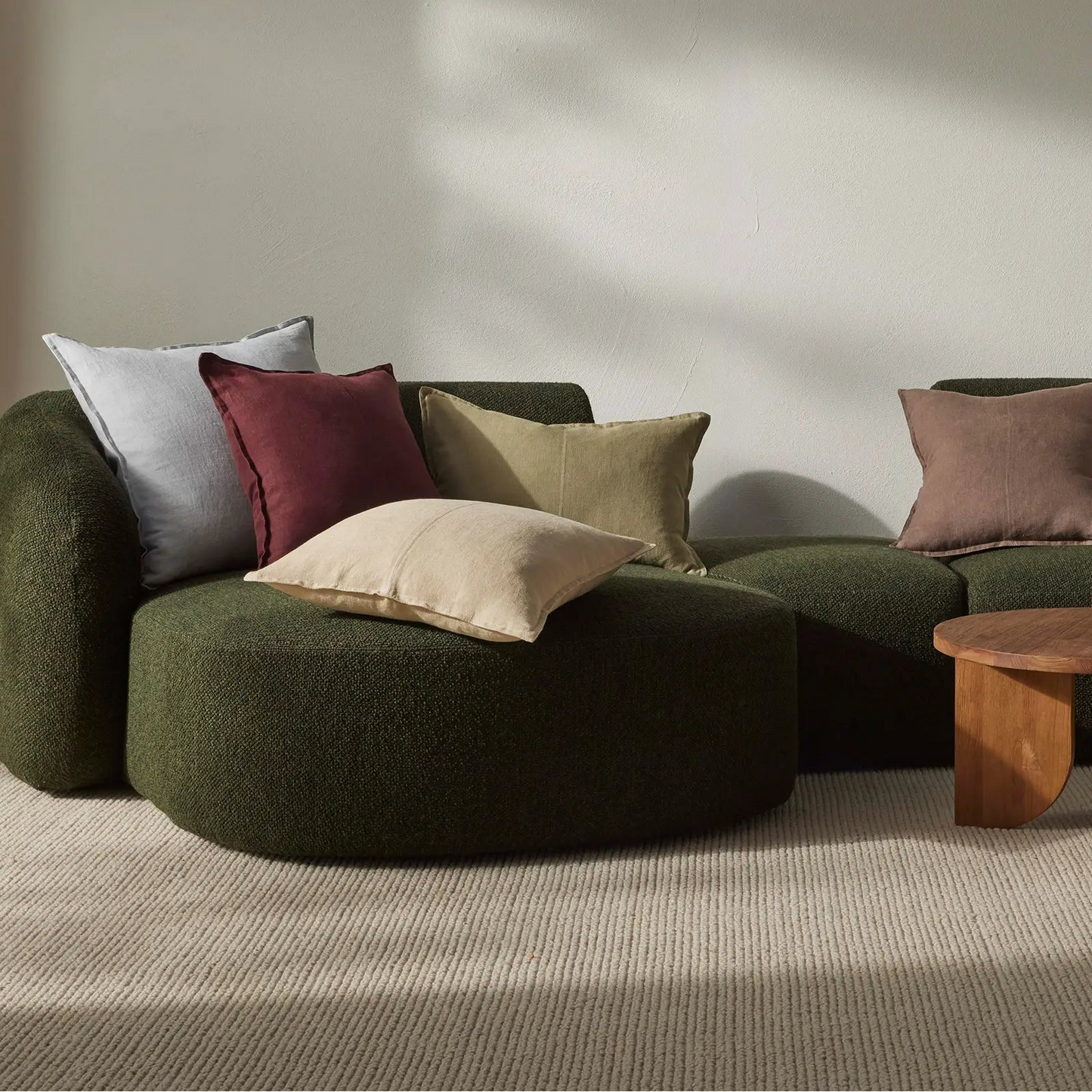Green sofa with colorful cushions in a minimalistic room