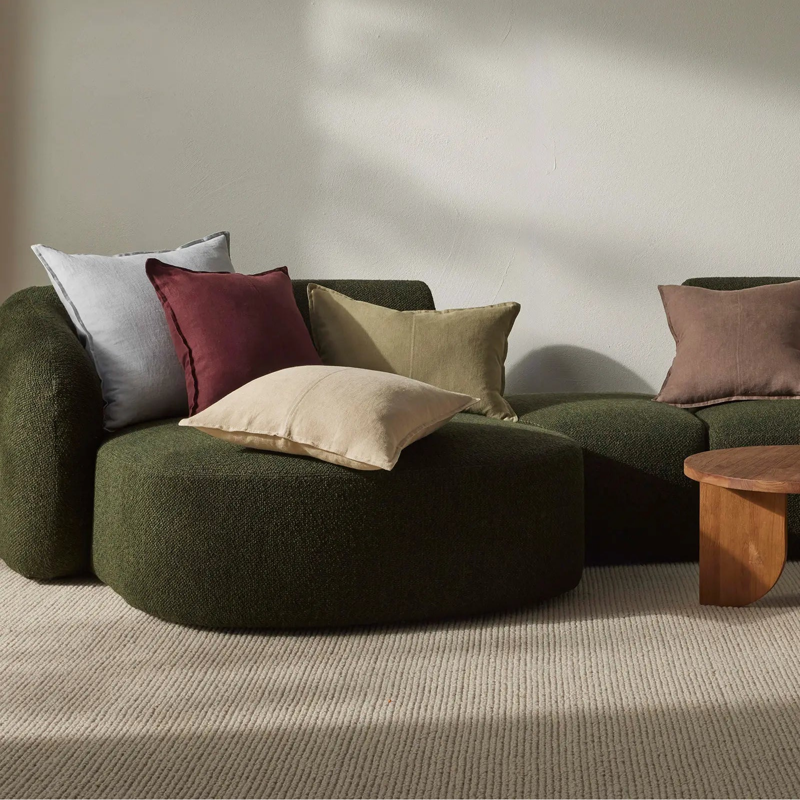Green sofa with colorful cushions in a minimalistic room