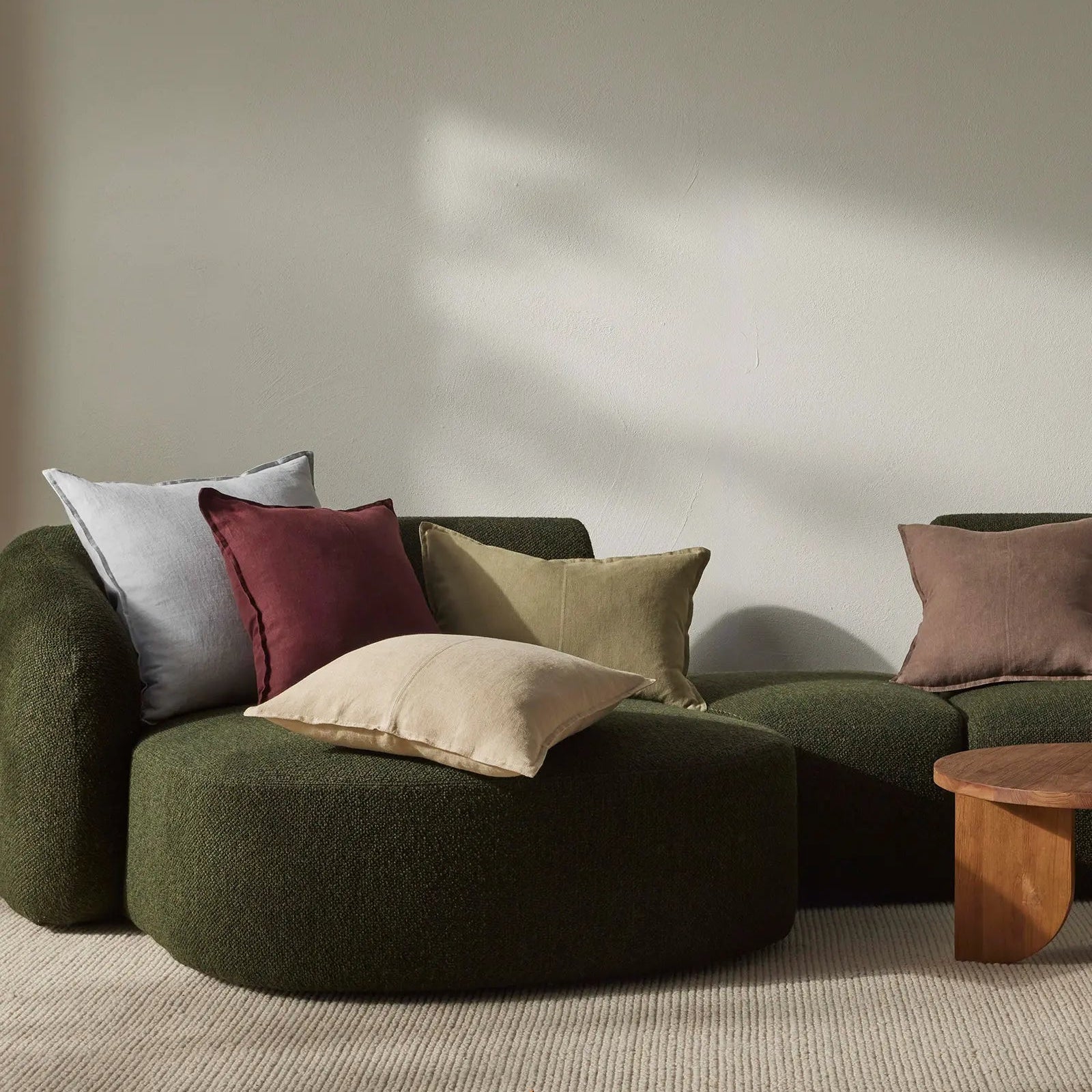 Green sofa with colorful cushions in a minimalistic room