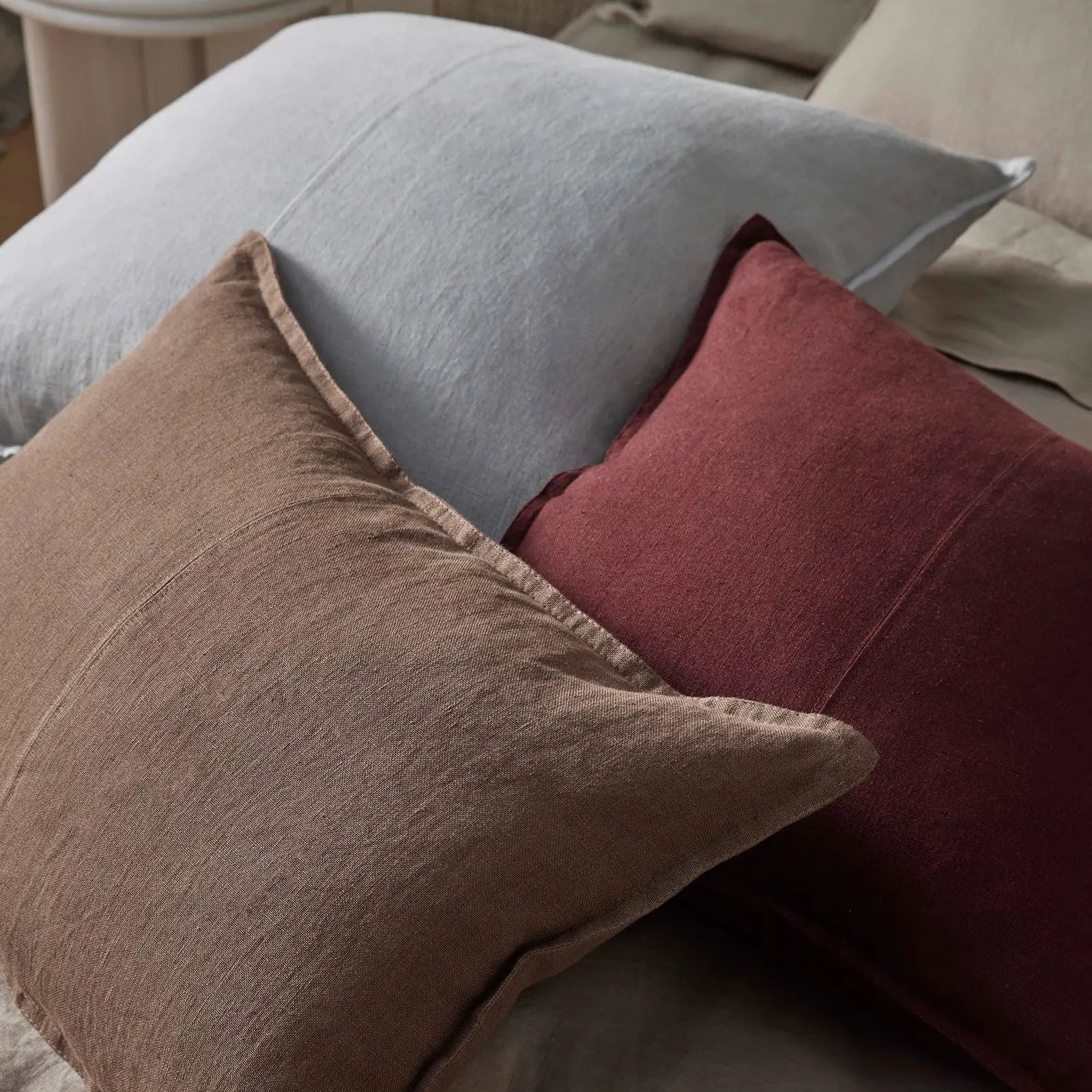 Three pillows in gray, brown, and red on a sofa.