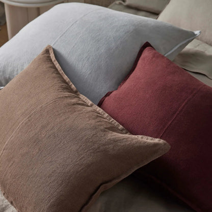 Three pillows in gray, brown, and red on a sofa.