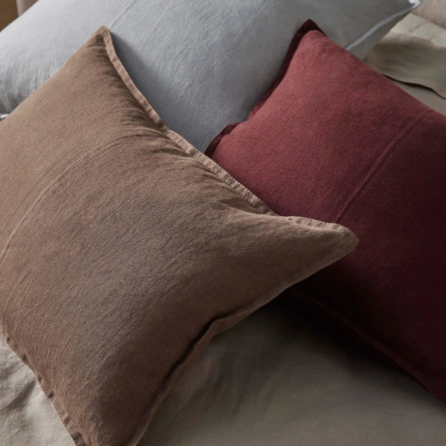 Three pillows in gray, brown, and red on a sofa.
