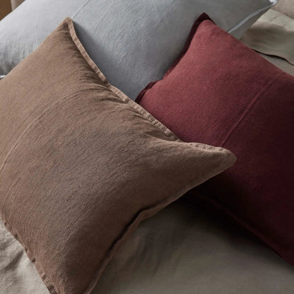 Three pillows in gray, brown, and red on a sofa.