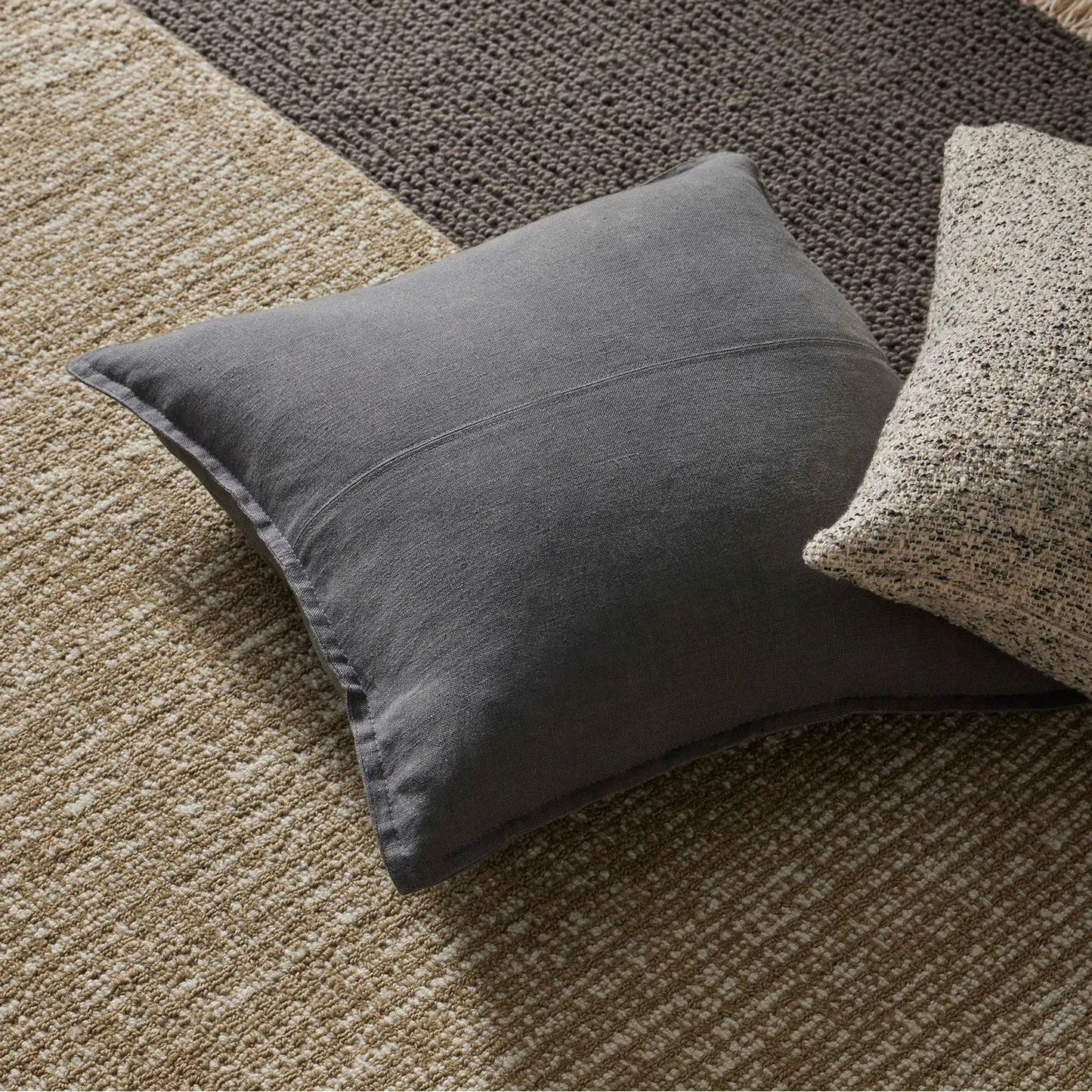 Gray pillow on a textured rug with wooden floor