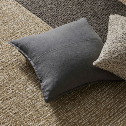 Gray pillow on a textured rug with wooden floor