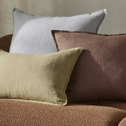 Three pillows in beige, brown, and gray on a textured surface.
