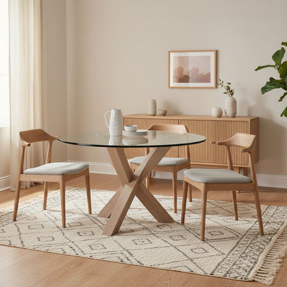 Round glass dining table with wooden cross plinth base in a neutral dining room setting 