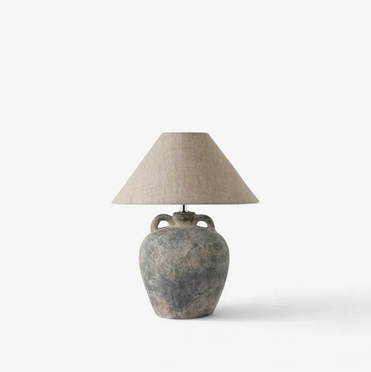 Table lamp with aged grey terracotta base and linen lampshade on a white background