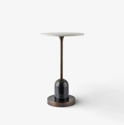 A modern side table featuring a round white marble top, a dark bronze metal stem, a glossy black glass cylindrical base, and a matching round bronze base plate, shown on a clean white background.