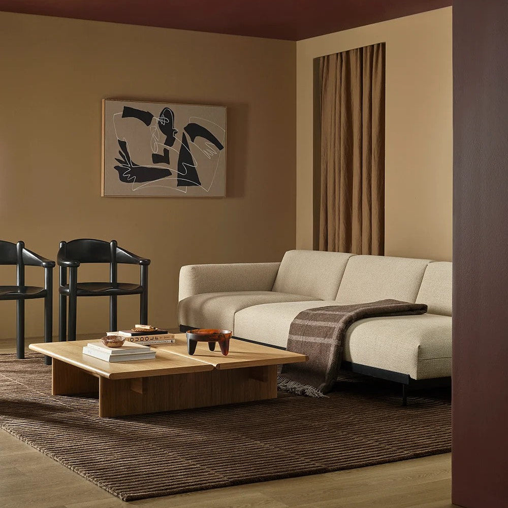 Modern living room with a beige sofa, wooden coffee table, plaid wool throw and abstract art on the wall.