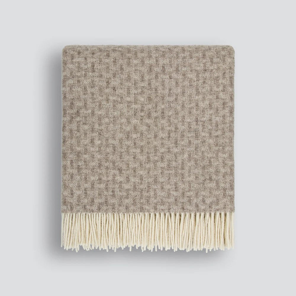 Textured throw blanket with twisted tassel edges on a white background