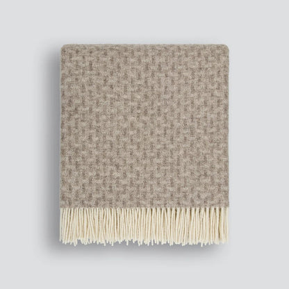 Textured throw blanket with twisted tassel edges on a white background