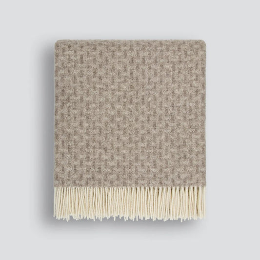 Textured throw blanket with twisted tassel edges on a white background